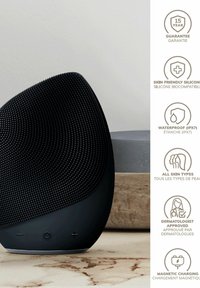 Haut-parleur en silicone noir avec surface texturée, design arrondi, boutons de contrôle à la base et accent métallique brillant. Étanche (IPX7).