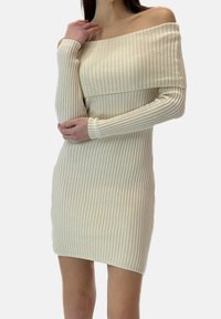 Vestido de canalé con escote de hombros descubiertos en color blanco roto. Mangas largas, corte ajustado y tela texturizada con sutiles líneas verticales.