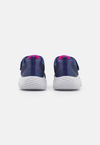 Baskets de sport bleu marine avec des accents roses, un dessus texturé et une sangle à bande auto-agrippante. Présentent une semelle blanche striée pour l'adhérence.