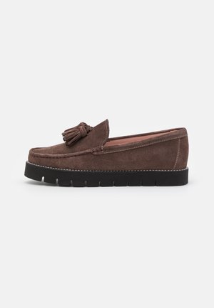 Mocassins à enfiler en daim marron avec un accent à pampilles, dotés d'une épaisse semelle en caoutchouc noire et de coutures blanches contrastantes le long du bord.