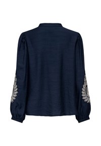 Blouse bleu marine à manches longues avec manches bouffantes et broderie florale blanche sur le bas des manches, vue de dos.