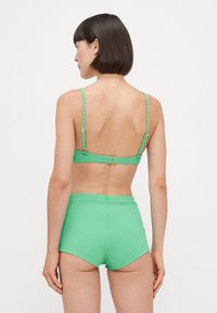 Set da bagno verde a coste composto da un bralette con spalline sottili e pantaloni corti a vita alta, che presenta un tessuto a trama e hardware regolabile.