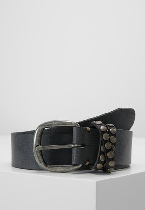 Sort læderbælte med et slidt sølvspænde og en nittebesat læderløkke, vist sammenrullet på en hvid overflade.