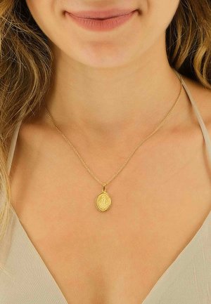 Collier en or avec un pendentif ovale présentant une figure gravée, suspendu à une fine chaîne, porté sur un cou nu.