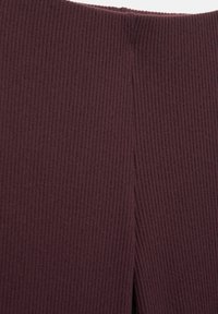 Geribbelde bordeauxrode stof met een gladde textuur en een gespleten detail aan de bovenkant. Close-up weergave die materiaal en ontwerp benadrukt.