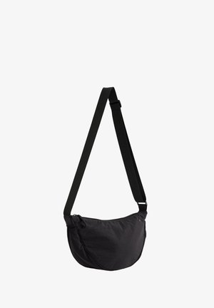 Juodos spalvos pusmėnulio formos rankinė per petį su reguliuojamu dirželiu ir užtrauktuko uždarymu, izoliuota ant balto fono.