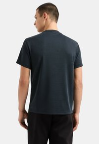 T-shirt grigio scuro a maniche corte, realizzato in tessuto morbido, con scollo rotondo e vestibilità comoda. Texture liscia con dettagli minimi.
