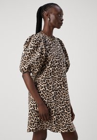 Sukienka w animal print z motywem lamparta, z bufiastymi rękawami, luźnym krojem, uszyta z miękkiego materiału o gładkiej teksturze, w odcieniach brązu i czerni.