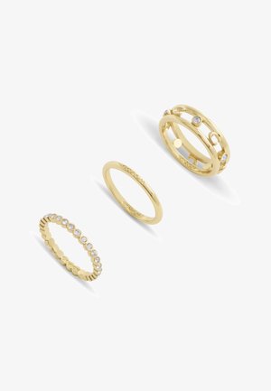 Tre anelli d'oro: un anello a banda liscia, uno con piccole gemme e un design a più anelli con ritagli circolari e accenti.
