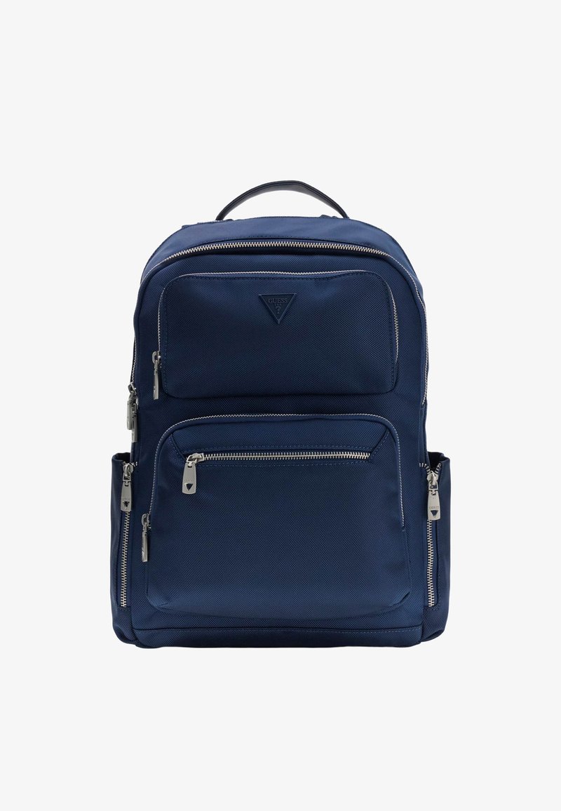 Sac à dos bleu marine avec plusieurs compartiments zippés, poches latérales, poignée supérieure et logo Guess sur la poche avant.