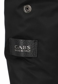 Matériau en nylon noir avec une étiquette en cuir texturé. Texte en relief argenté "GABS MADE IN ITALY" et détail en œillet métallique.
