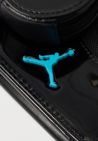 Superfície de verniz preto com um proeminente logótipo Jumpman azul, apresentando um detalhe texturizado e contornos suaves.