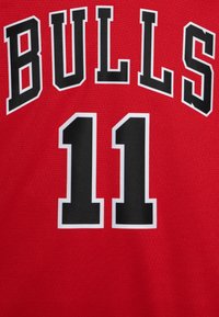 Maglia sportiva rossa con la scritta "BULLS" in grassetto nero sopra il numero "11". Il tessuto ha una finitura testurizzata e traspirante.