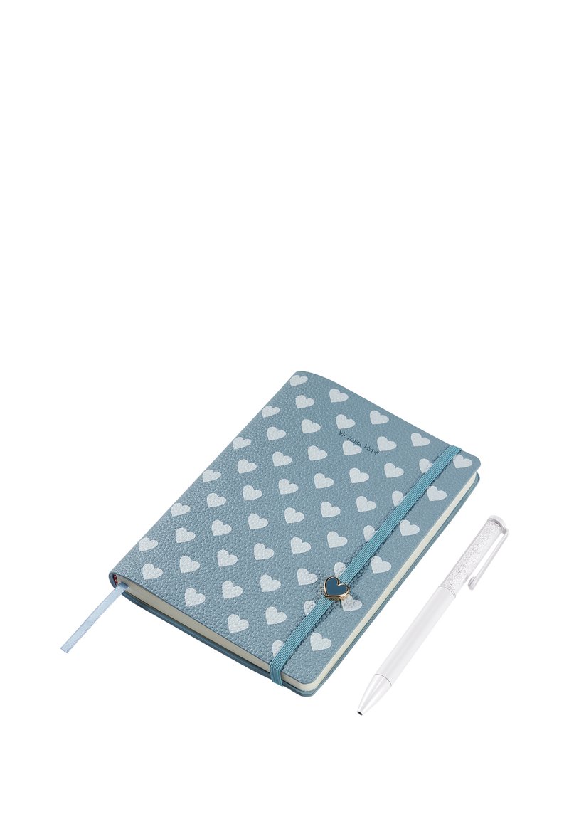 Blue notebook with white hearts, elastic band with heart-shaped charm, and white pen with glitter near it on a white background.