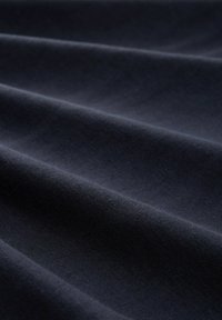 Donkerblauwe stof met een zachte textuur, gekenmerkt door gladde, vloeiende plooien en een consistente weefpatroon.
