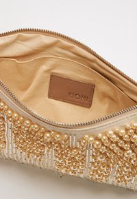 Kopertówka z koralikami, ozdobiona złotymi perłami i pasmami z przodu, wnętrze wykonane z beżowego materiału oraz skórzana etykieta KIOMI. Zamknięcie na zamek błyskawiczny u góry.