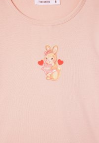 Camicia in cotone rosa chiaro con una grafiche stampata di un coniglio che tiene una stella con il testo "magia", arricchita da cuori rossi e scollo rotondo.