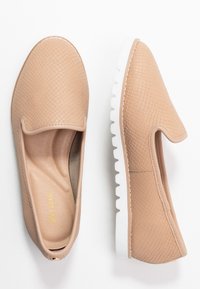 Scarpe slip-on beige chiaro con superficie testurizzata, suola bianca e design a profilo basso. Presentano un interno morbido.