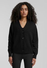 Zwarte cardigan van gebreide stof, met een V-hals, vier knopen aan de voorkant en ribborstels en zoom.