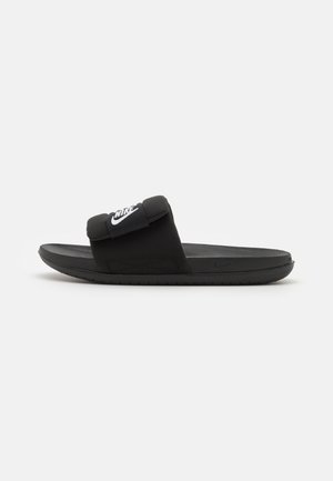 Čierna plážová obuv so zosilneným popruhom, na ktorom je biele logo Nike. Dizajn zahŕňa textúrovanú stielku a gumovú podrážku.