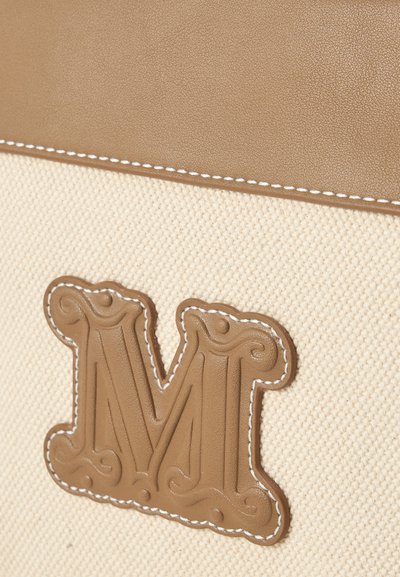 Beige stof met lichtbruine lederen afwerking en een gestikte lichtbruine lederen embleem met een decoratieve letter "M" met gegraveerde details.