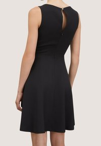 Mustat hihattomat mekko, jossa on istuva yläosa, kellotettu helma ja avokuja selässä, jossa on nappikiinnitys kaula-aukossa.