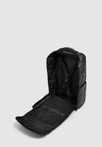 Mochila de cuero negro con cierre de cremallera, interior espacioso, correas ajustables y compartimentos de malla con cremallera para organización.