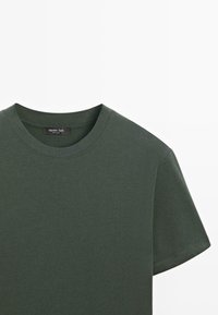 Maglietta verde scuro a maniche corte realizzata in tessuto liscio e leggero; presenta un classico girocollo e un design minimalista con un'etichetta visibile.