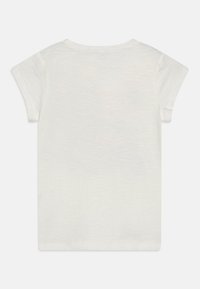 Kortermet t-skjorte med rund hals i lys beige stoff. Myk, litt strukturert overflate med en avslappet passform. Ingen synlige grafikker eller mønstre.