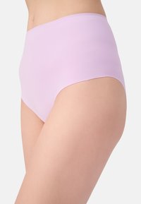 Donna che indossa lingerie lavanda seamless a vita alta, in evidenza fianchi e parte superiore della coscia su uno sfondo bianco.