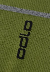 Πράσινο πλεκτό ύφασμα που παρουσιάζει ένα υφασμάτινο σχέδιο με μια γκρι οριζόντια λωρίδα. Διαθέτει μαύρα γράμματα και σχέδια. Η υφή φαίνεται μαλακή και ζεστή.