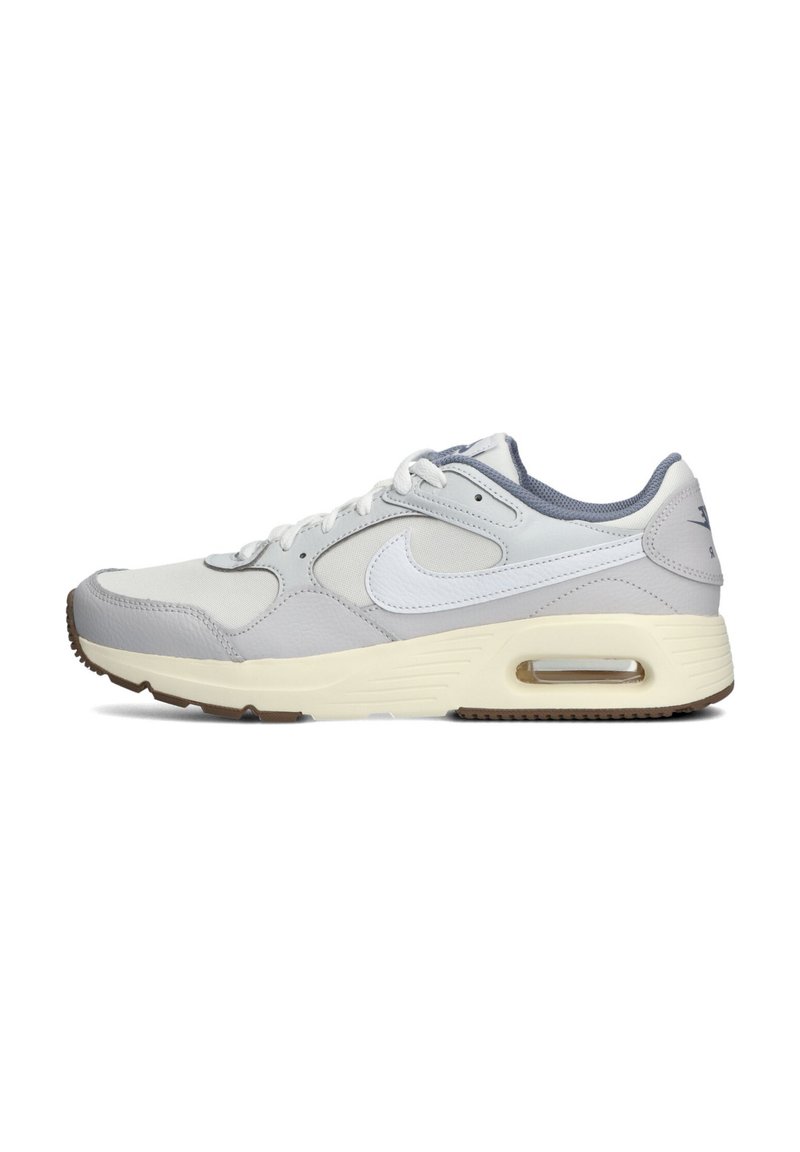 Zapatilla deportiva gris con parte superior de cuero y textil, que presenta detalles en blanco, un cojín de aire visible y una suela de goma con surcos de tracción.