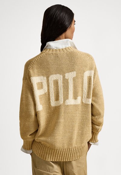 Pleteni pulover svetlo rjave barve z ohlapnim krojem, na hrbtu z napisom "POLO" v kremni barvi ter z rebrastim robom in manšetami.
