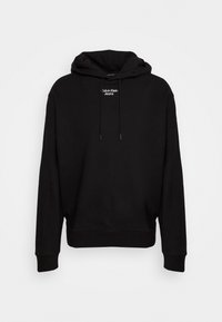Černá mikina s kapucí vyrobená z měkké látky, s přední kapsou, nastavitelými šňůrkami a malým bílým logem "Calvin Klein Jeans" na hrudi.
