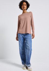 Helles rosa, langärmliges Sweatshirt mit einem Carmen-Ausschnitt, kombiniert mit lässigen hellblauen Jeans und weißen Sneakers. Glatte Textur, lässiger Stil.