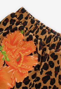 Brūns audums ar leoparda rakstu un lieliem, spilgti oranžiem ziedu motīviem. Redzama gluda tekstūra un elastīga jostas detaļa.