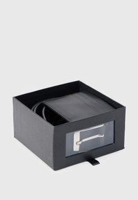 Μαύρη δερμάτινη ζώνη σε ορθογώνιο μαύρο κουτί με διαφανές μπροστινό μέρος. Διαθέτει ασημένια μεταλλική πόρπη και ραμμένες λεπτομέρειες στη ζώνη.