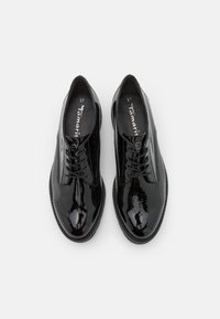 Scarpe in pelle verniciata nera con punta rotonda, design con lacci e texture liscia, caratterizzate da una suola sottile e semplici dettagli di cucitura.