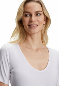 Top bianco a maniche corte con scollatura a V profonda, caratterizzato da una texture liscia e una silhouette aderente. Stile minimalista senza pattern.