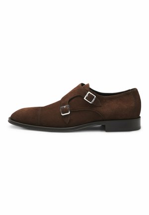 Brown suede double monk strap shoes featuring silver-tone buckles, a pointed toe, and a flat rubber sole. Smooth texture with minimal stitching.