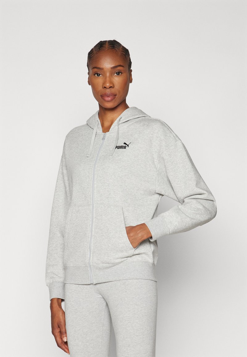 Grå zip-up hoodie gjord av mjukt material, med en huva, kengurufickor och en liten svart Puma-logotyp på den övre vänstra sidan.