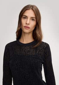 Maglia nera a maniche lunghe con un motivo testurizzato a coccodrillo, con scollatura rotonda e tessuto morbido.