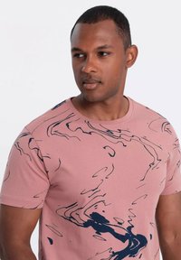 T-shirt rosa a maniche corte con un motivo astratto blu. Realizzata in tessuto morbido, presenta un collo a giro e una vestibilità comoda.