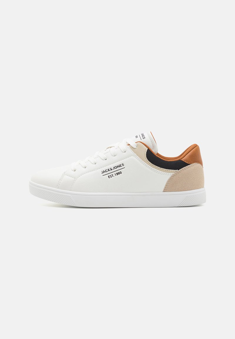White sneaker with leather and suede accents in beige and brown. Features a textured sole, rounded toe, and lace-up design.