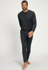 Langärmliges schwarzes Thermoshirt und passende, enganliegende Hosen. Weicher, texturierter Stoff mit einem markierten Bund. Designed für Wärme und Komfort.