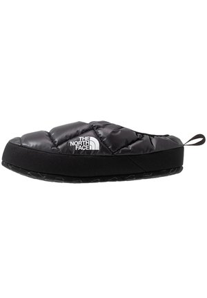 Chausson slip-on isolant noir avec dessus matelassé, logo The North Face et semelle en caoutchouc noire avec une languette arrière.
