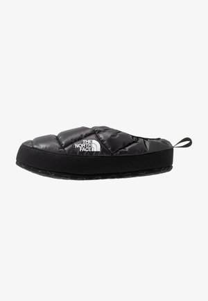 Chausson slip-on isolant noir avec dessus matelassé, logo The North Face et semelle en caoutchouc noire avec une languette arrière.