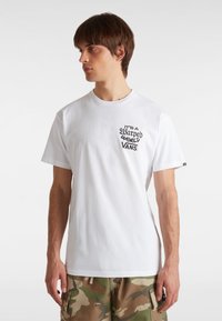 Witte katoenen t-shirt met een zwarte opdruk "It’s a Warped World" en het Vans-logo op de linkerborst. Ronde halslijn en korte mouwen.