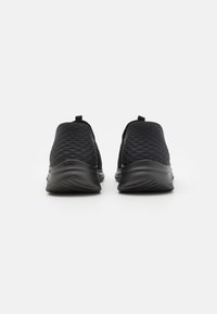 Fekete slip-on sportcipők, texturált felsőrésszel, kerek orral és rugalmas talppal. Párnázott bokazuhanyt és húzófület tartalmaz a könnyű felvétel érdekében.