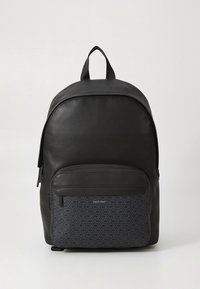 Černý kožený batoh s hladkým povrchem, který má vzorovanou přední kapsu v tmavě šedé barvě, nastavitelné popruhy a horní úchyt.